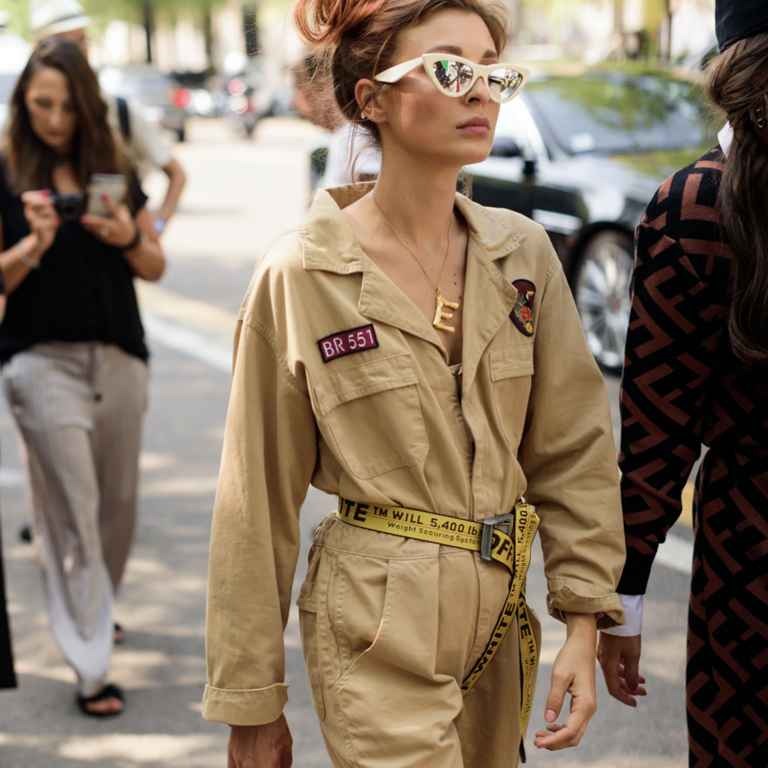 Street tyle photo of a fashionista wearing a bege jumpsuit with patches and off-white yellow belt