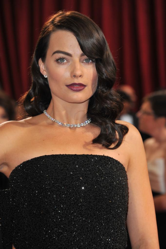 Margot Robbie wearing a strapless black gown and her original black hair