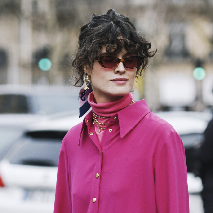 Woman layers pink turtleneck under summer dress to transition to fall