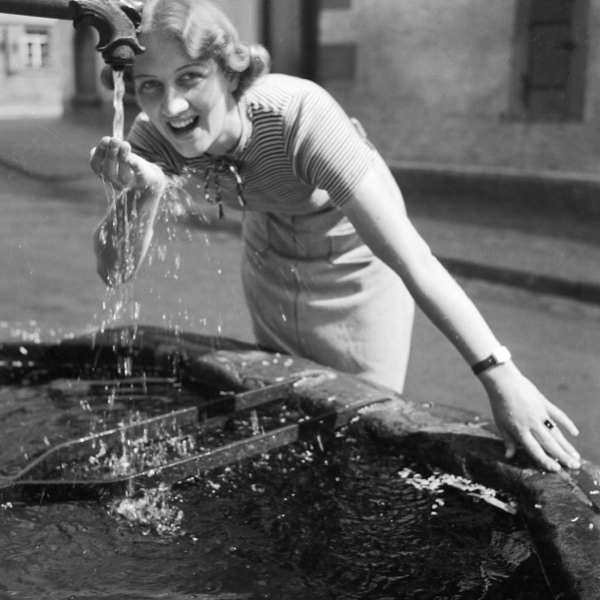 Woman smiling while she drinks enough water from fountain.