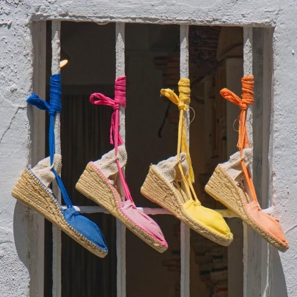 espadrilles in different colours and tied up on the bars of a window
