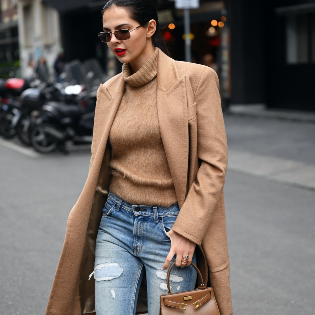 fahiionista during milan fashion week wearing a cashmere turtleneck pullover, camel coat and a distress jeans