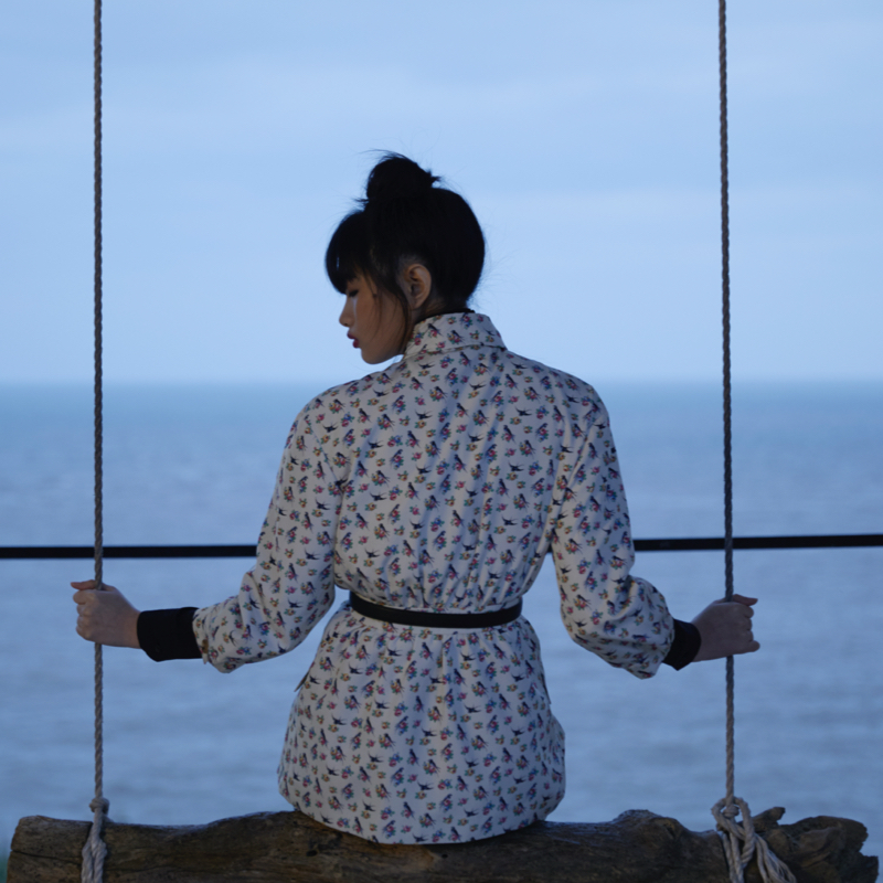 Asiatic model sit on a swing contemplating the lake