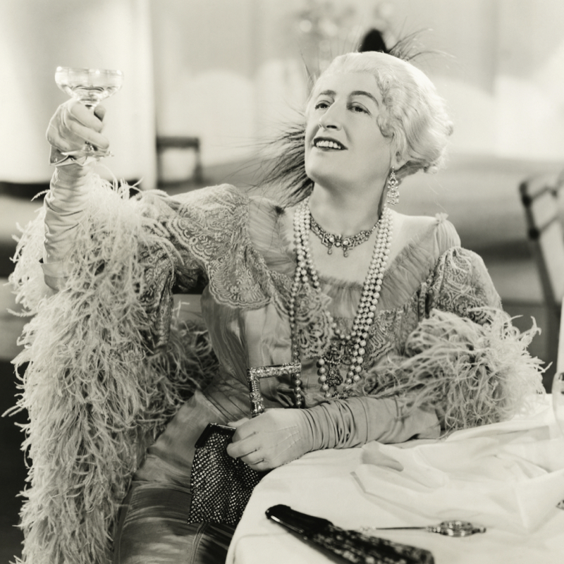 VIntage image of a chic woman raising her glass of champagne to make a toast as a wedding party.