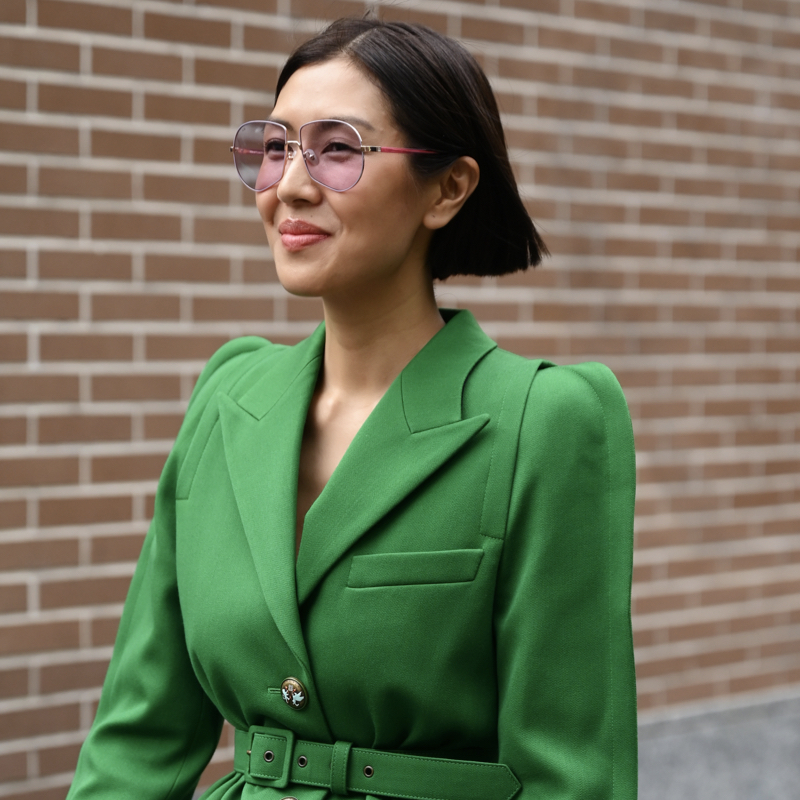 Stylish woman during Fashion Week wearing 1940s fashion style belted jacket with puffy shoulders.