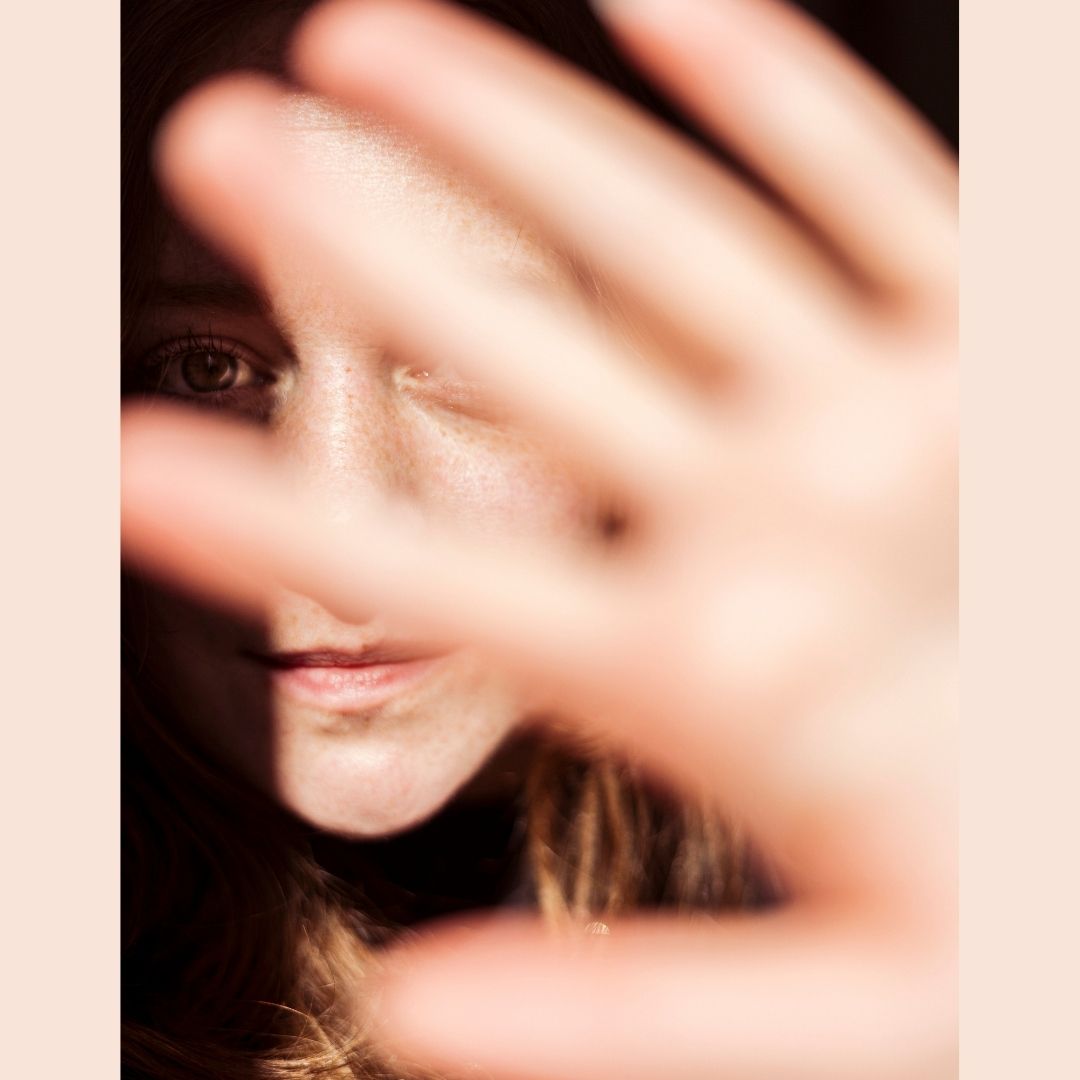 Woman protects her face from the sun using her hands