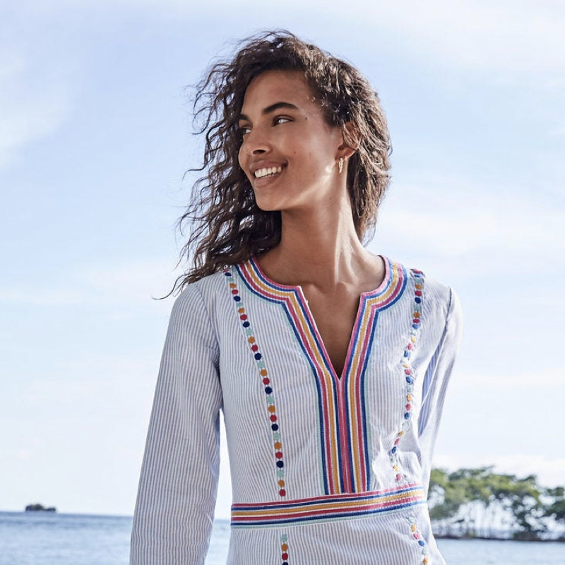 Woman at the beach wearing an embroidered kaftan-style dress.