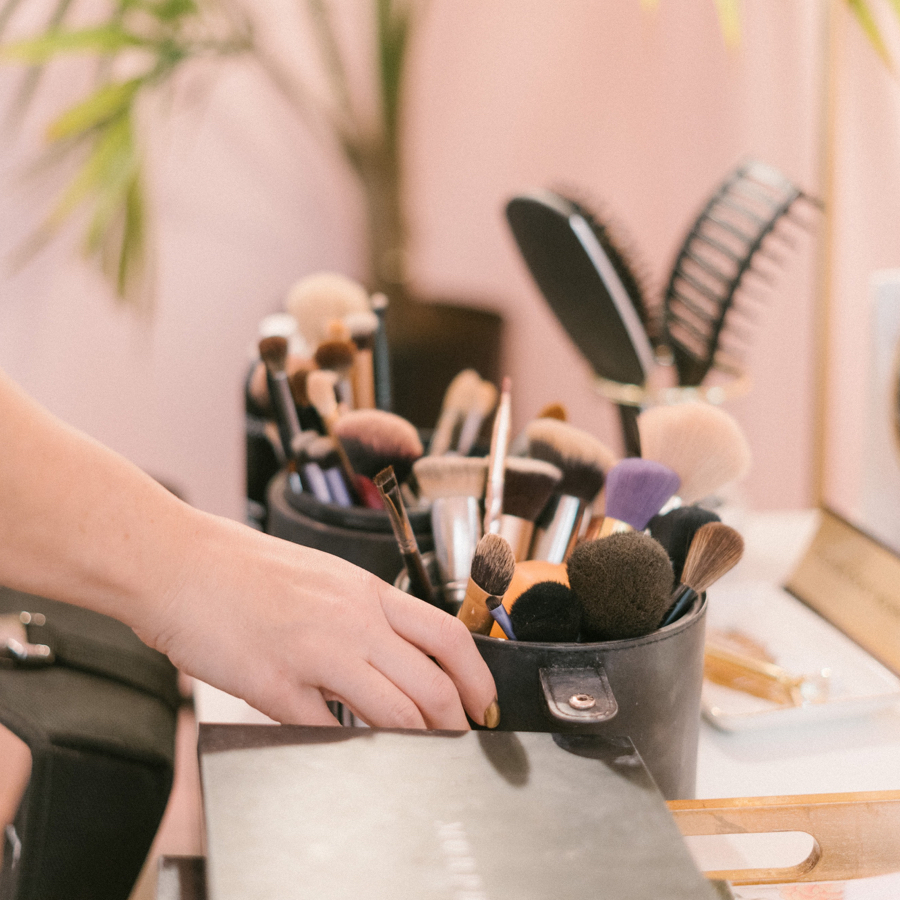 woman hand grabs some makeup brushes from a makeup table