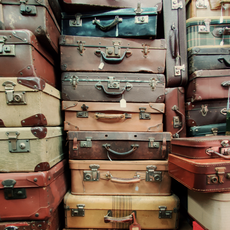 Travel bags and weekend bags in several colours piled up.