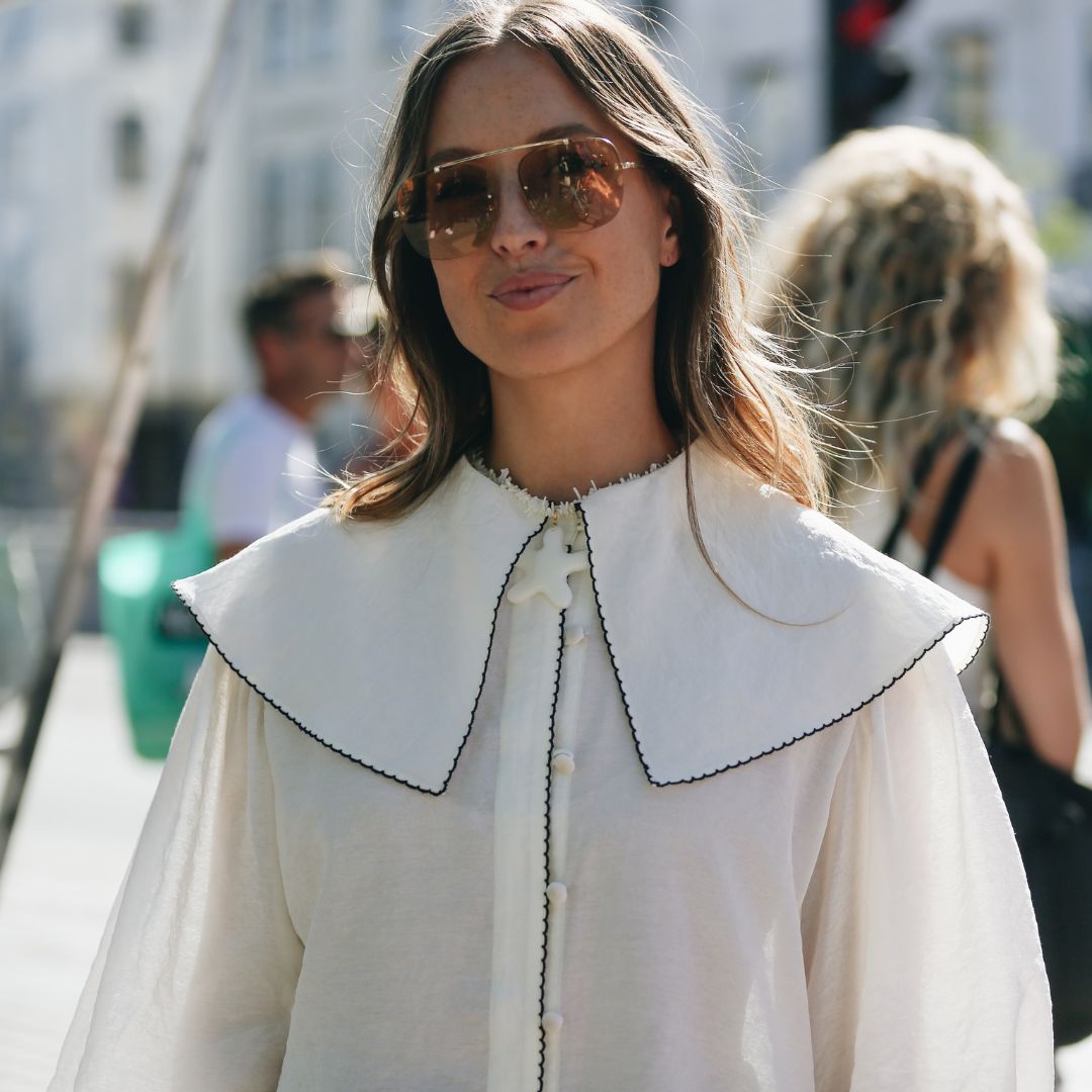 fashionista at Copenhagen Fashion Week wearing a white shirt with a oversized collar and sunglasses