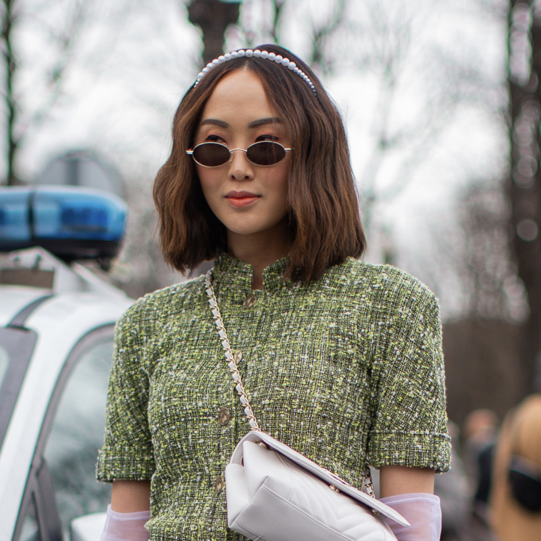 Fashion show goer wearing Chanel green bouclé dress in spring.