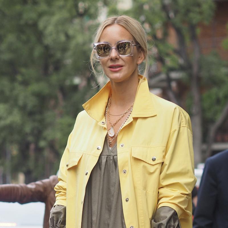 Woman wears yellow outwear over beige dress.