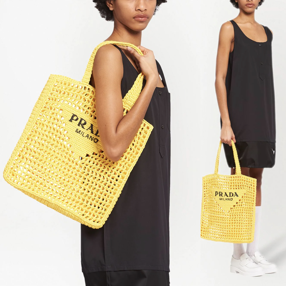 Model wearing a black dress and yellow raffia bag from Prada from Farfetch onlineshop