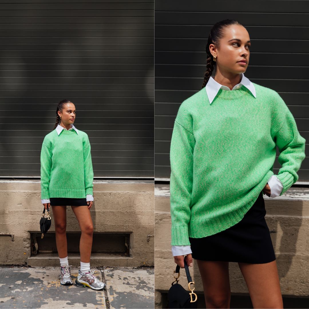 street style photo showing influencer wearing a lime green pullover and a black mini skirt paired with a dad sneaker