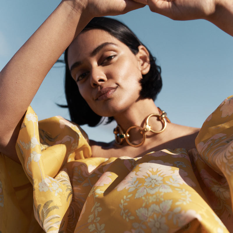 close up of a model watching to the camera and wearing a yellow floral dress