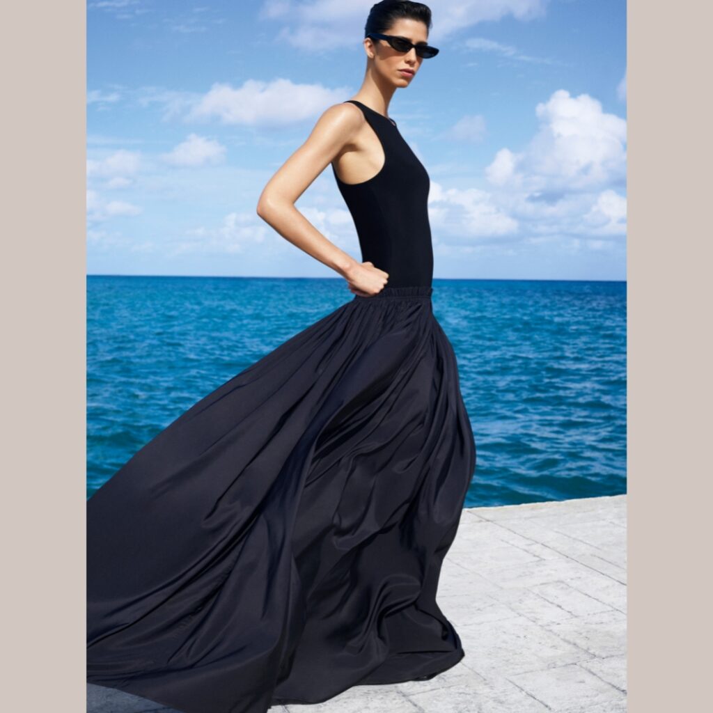 model wearing a long black dress in a pedestrian area in front of the beach