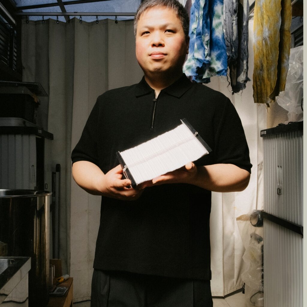 Artist Kazuki Tabata in his atelier in Osaka, holding a tool which he uses to create his Shibori