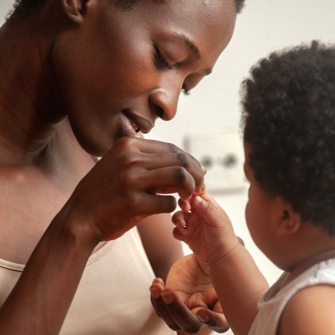 detail of a black mother playing with the little hands of her child