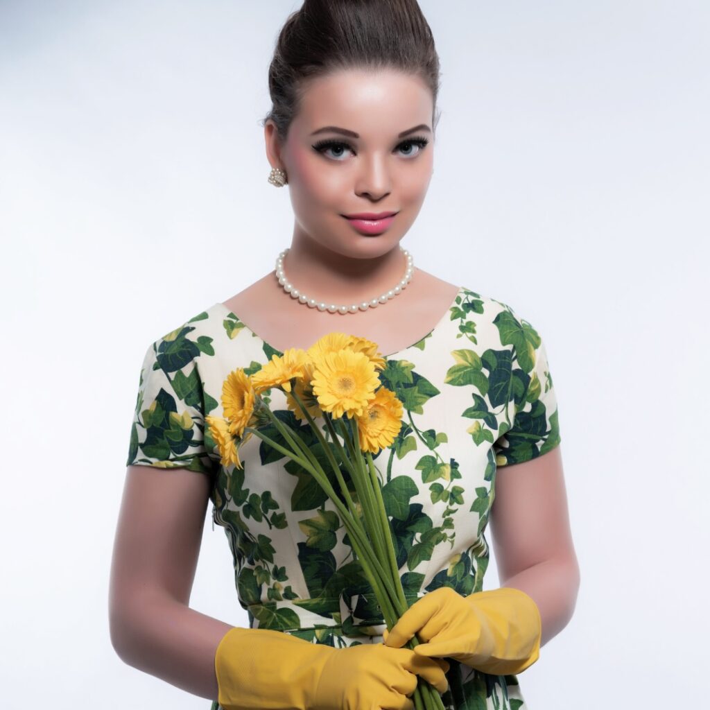 tradwife aesthetic-young woman wearing a flowered dress, carries a flower bouquet while wearing a rubber yellow gloves