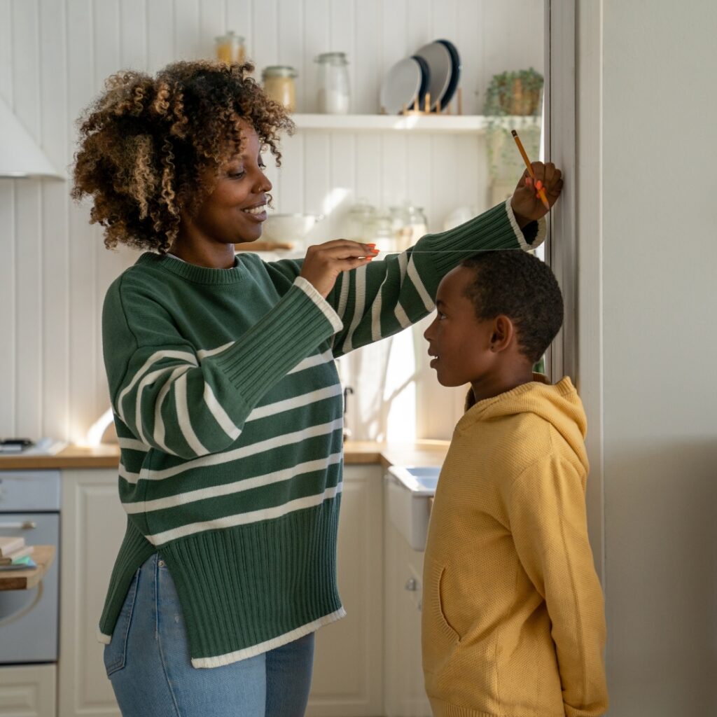 Mother marking on the wall how tall her son is  