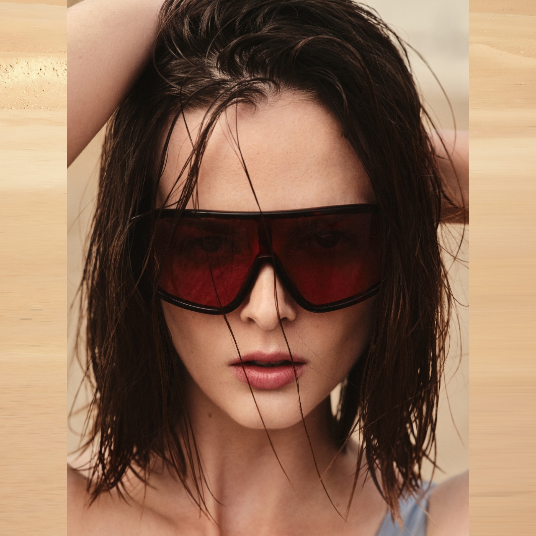 closeup of a COS model with wet hair on the beach, wearing a big sunglasses