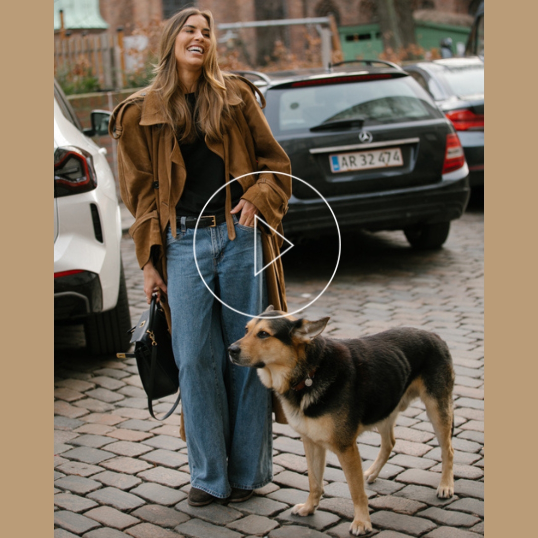Fashionista with her dog pet, wearing a denim pants while walking in the streets of copenhagen