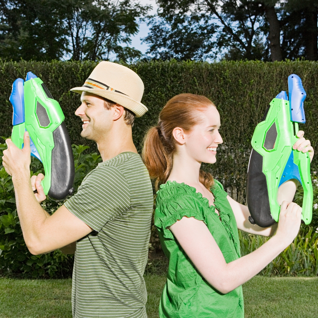 couple in a garden ready for a duell using two water pistols