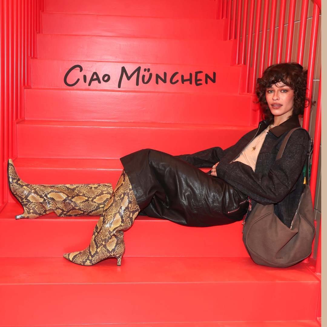 Melanie Kieback sits on the steps of a red stair in the new Max&Co shop in Munich