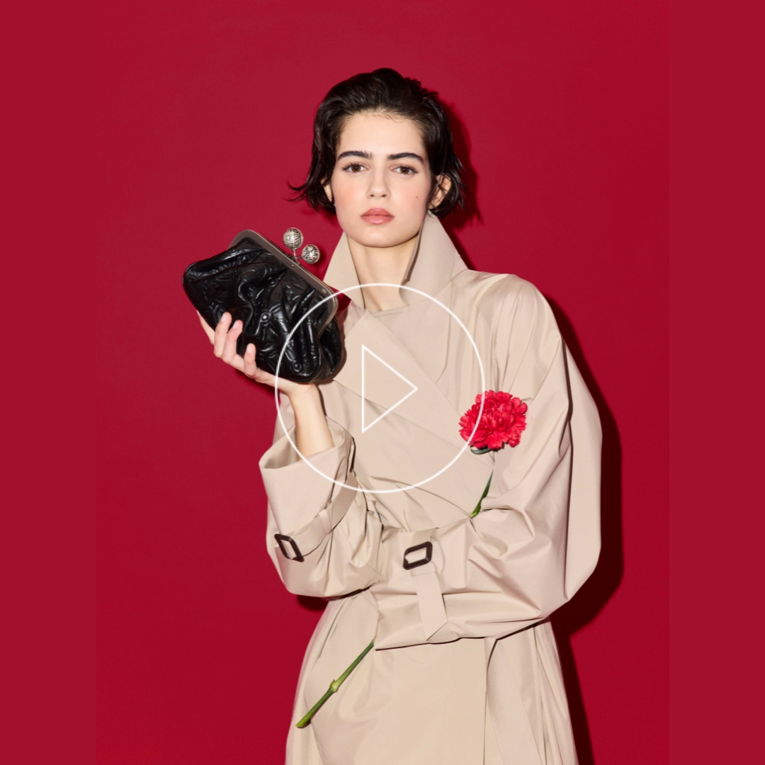 weekend Max Mara model wearing a trench coat, holds a Pasticcino bag. A red flower on her lapel reminds the spanish craft heritage of the bag