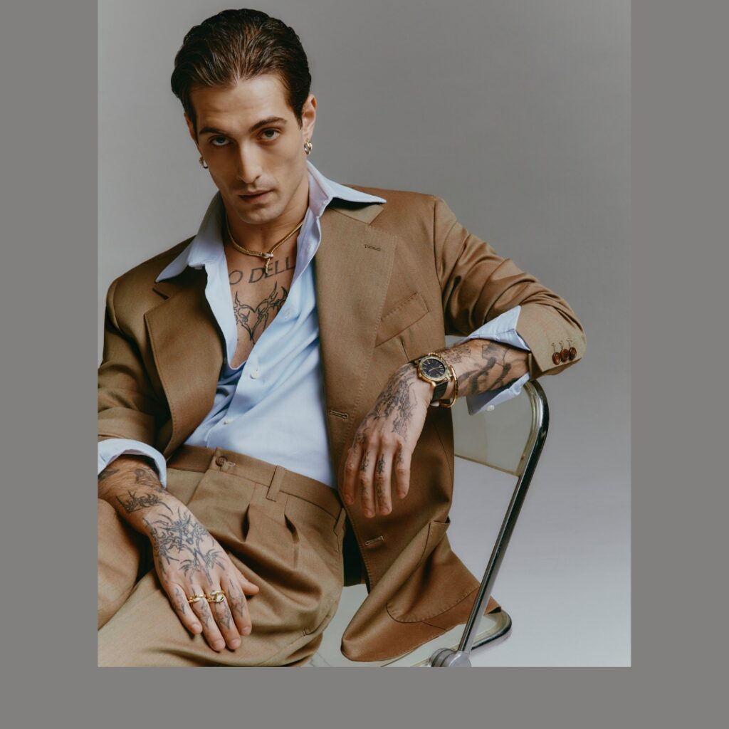 Damiano David in a classic camel suit wearing necklace, earrings, rings and bracelet from Bvlgari