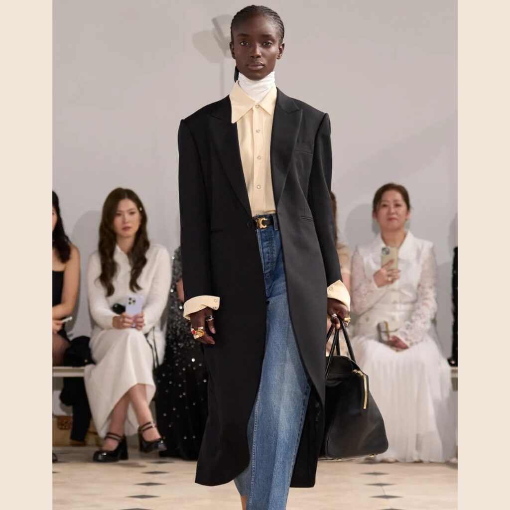 Model at Celine runway SS26 wearing a beige shirt with the collar and sleeves over the coat