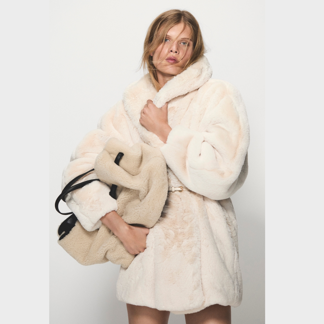 Model wearing creamy faux fur coat from COS Festive Collection 2025