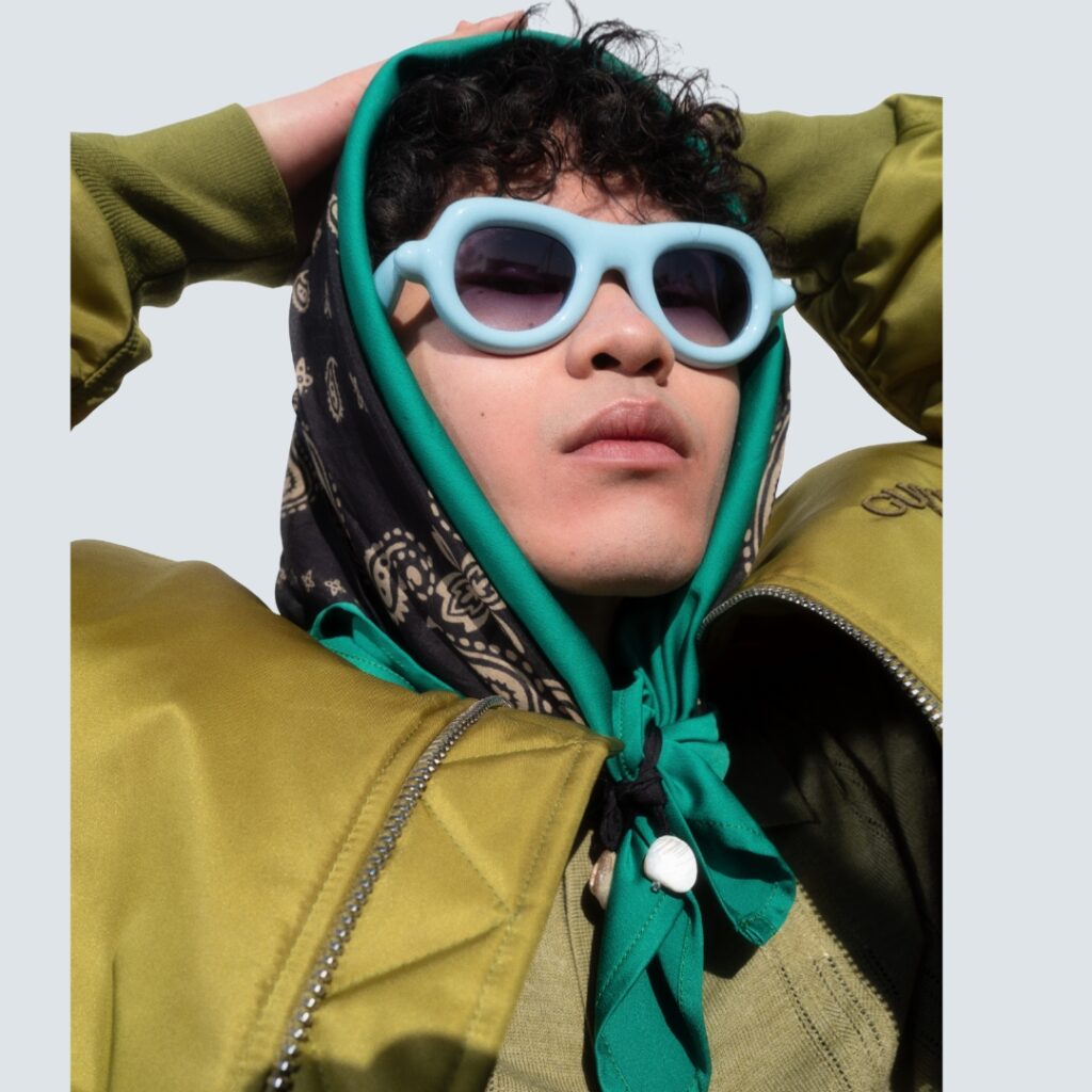 Model wearing Paloceras Pebble sunglasses in vibrant red acetate, editorial lighting.