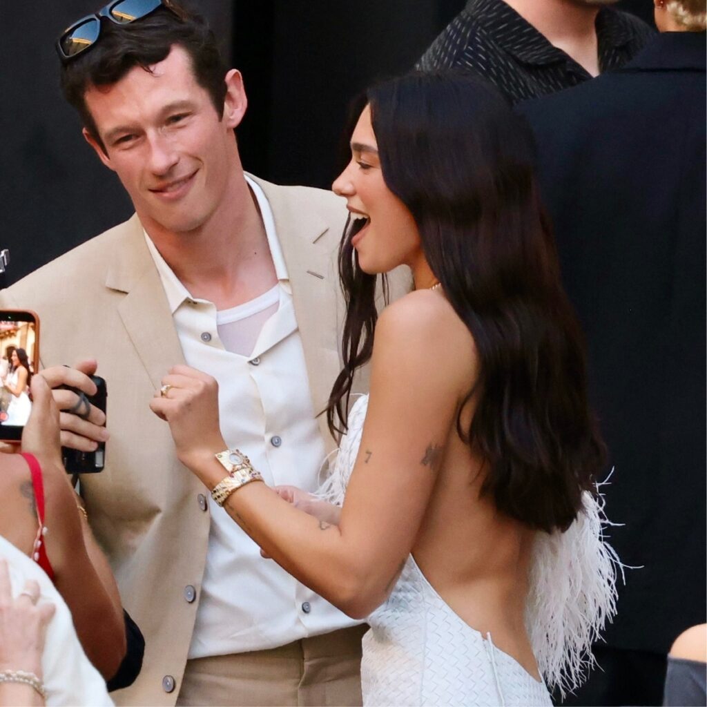 Dua Lipa and Callum Turner taking a photo outside the church in Palermo